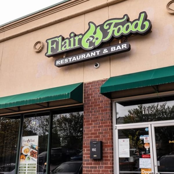 Exterior of Flair Food Restaurant and Bar, with green awnings and a prominent sign.