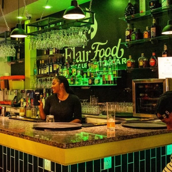 A bartender smiles while working behind a well-stocked bar at Flair Food Restaurant and Bar.