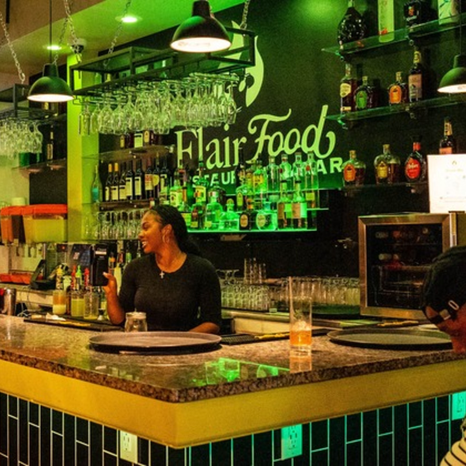 A bartender smiles while working behind a well-stocked bar at Flair Food Restaurant and Bar.